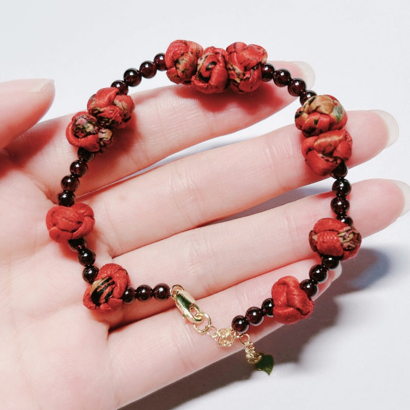 Xiangyunsha silk rose knot bracelet in crimson, product flat lay on white background